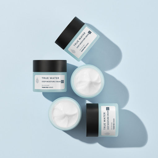A jar of THANK YOU FARMER True Water Deep Moisture Cream EX with a small amount of cream placed beside it, on a light blue background.