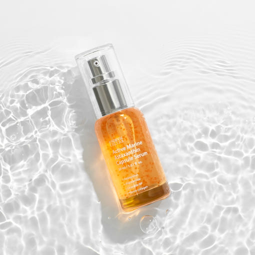 Glass bottle of Astaxanthin Serum with visible orange capsules in clear base